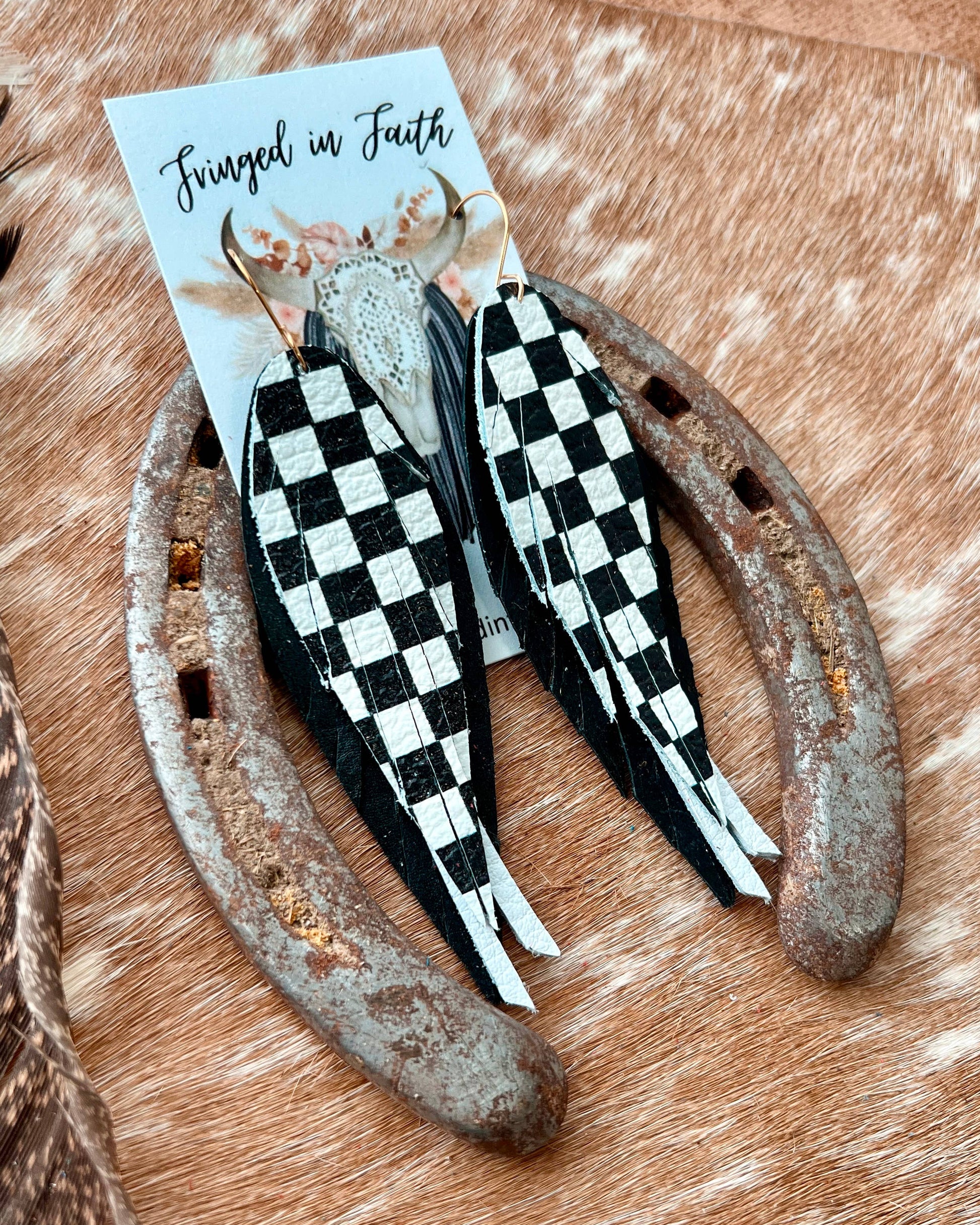 Black and white checkered feathers on a wooden surface with a card in the background.