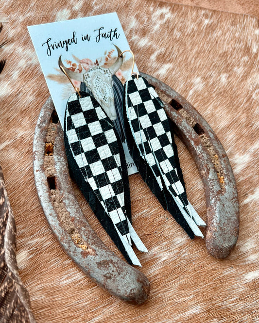 Black and white checkered feathers on a wooden surface with a card in the background.